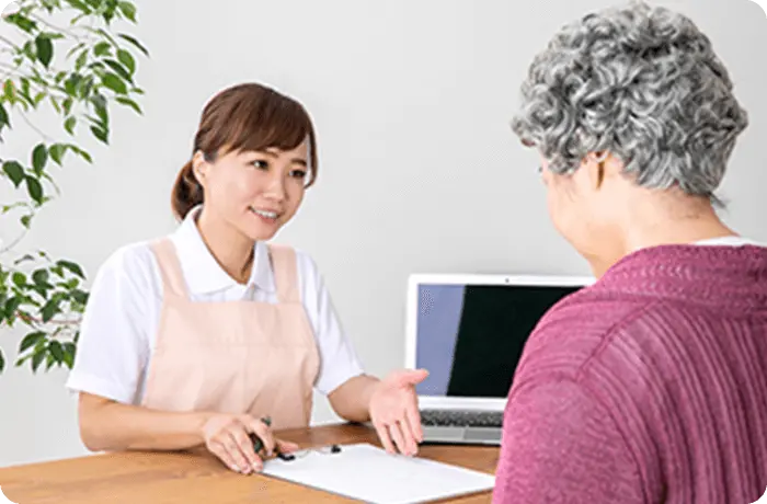 お年寄りの女性が手続するのを若い女性が親切に手伝う様子の画像